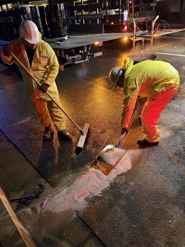 Two SpillSafe crew members collecting absorbent from a roadway